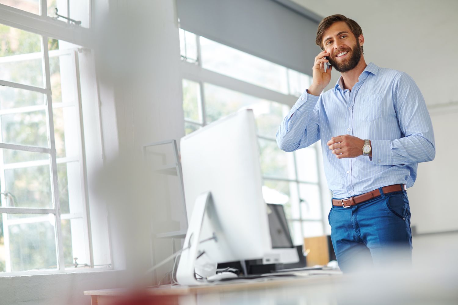 smiling man speaking on phone at work